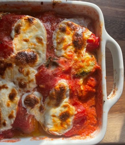Eggplant parmesan baked in a white dish with melted fresh mozzarella.