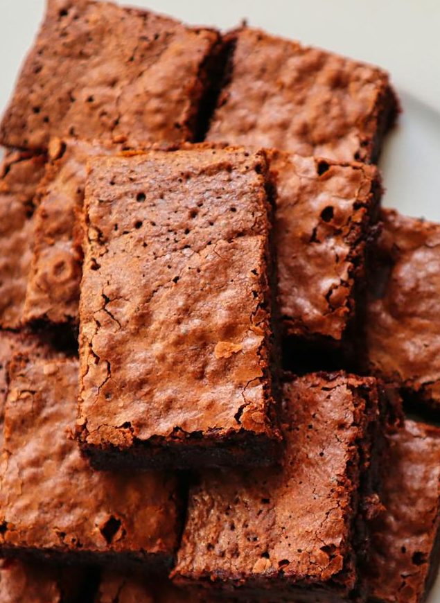 A bunch of brownies stacked on a white plate.