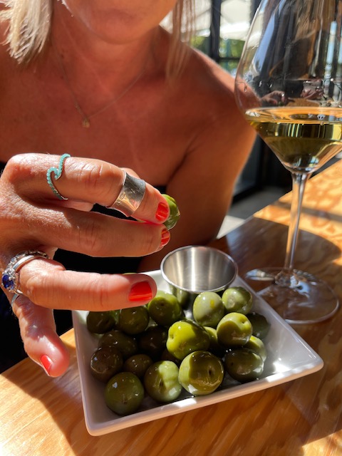 woman eating olives and drinking wine.