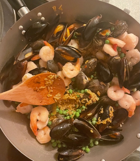 Seafood and rice cooking in a large pan.