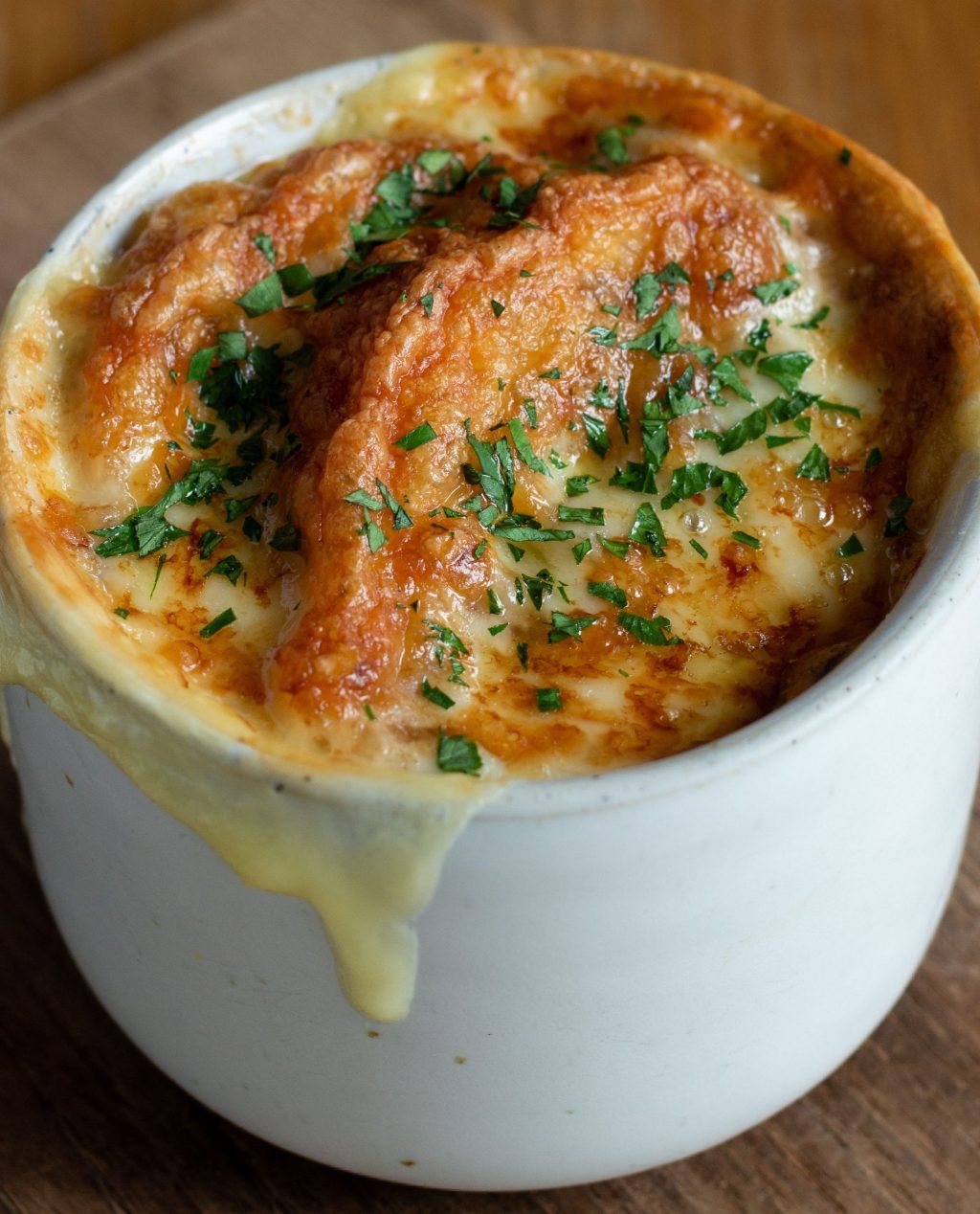 French onion soup with melted cheese on top in a white bowl.