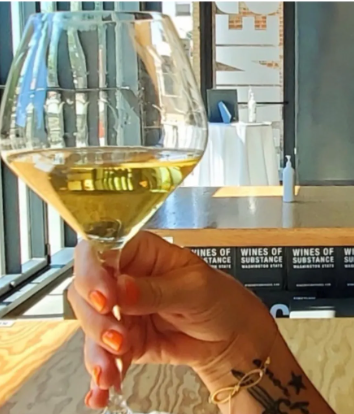 A woman's hand holding a glass of white wine.